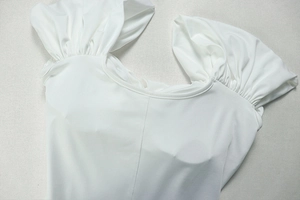 Close-up of pleated ruffle shoulder detail and high-quality stitching on white elegant dress