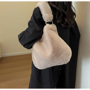 Detail of beige faux fur shoulder bag with gold metal rings on a wide strap