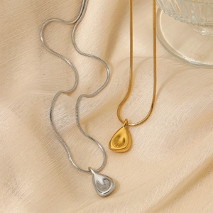 Minimalist gold and silver teardrop pendant necklaces on champagne silk background