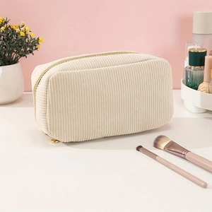 Detail of beige corduroy toiletry bag with golden zipper on a clean vanity desk