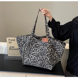 Close-up of leopard print canvas tote bag with brown leather accents and metal rivets