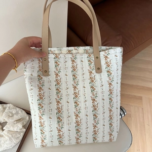 Détail du sac cabas en coton fleuri avec des poignées en cuir beige et rivets
