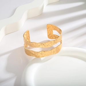 Detail view of gold open cuff bracelet with dual-layer cutout design and hammered texture