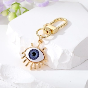 Golden Evil Eye keychain with resin pendant on white stone base with soft floral decor