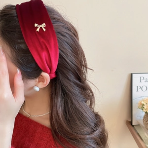 Detailed close-up of a red velvet headband with a tiny gold bow and soft elegant texture