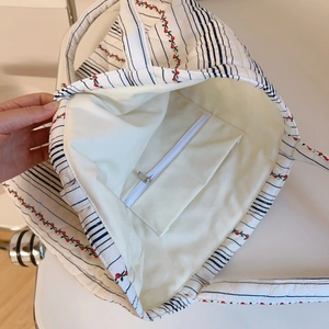 Détail de l'intérieur du sac matelassé à fleurs montrant la doublure et la poche zippée