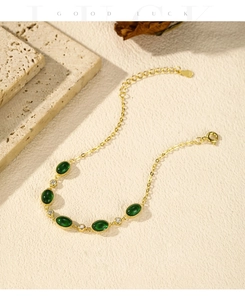 Detail of S925 silver gold-plated bracelet with emerald-green stones and white zircons