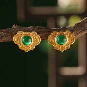 Macro shot of retro gold flower earrings with green stones on a branch