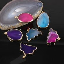 Macro detail of various natural agate pendants with gold plated edges on black background