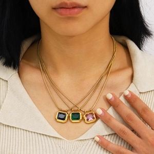Trois colliers en acier doré avec pendentifs carrés en zircon coloré portés par un modèle