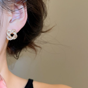 Detail of gold-plated intertwined hollow heart earrings with shimmering zircon stones