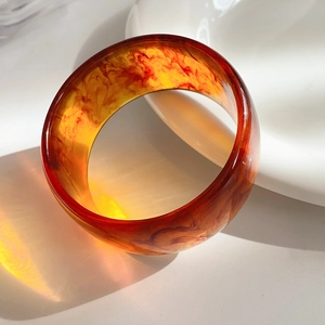 Detailed view of amber resin bangle showing marble texture and light transparency on ceramic