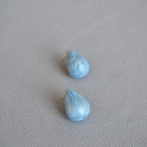 Detail of pear-shaped drop earrings with blue marble enamel and gold plating