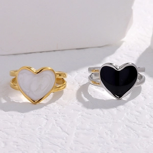 Detail of minimalist heart-shaped rings in gold marble and silver black on stone texture