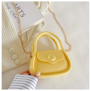 Top view of mini yellow jelly handbag with gold chain strap on a white dress
