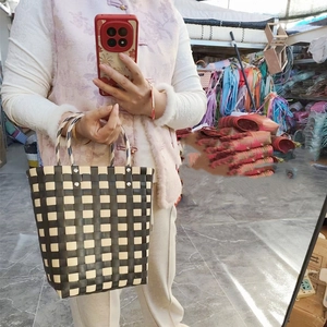 Close-up of checkerboard pattern on handmade woven bucket bag with rivet handles