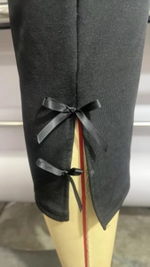 Detail showing the side slit with two decorative black ribbon bows on black pants leg