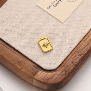 Detailed macro view of an 18k gold rectangular pendant with starburst and zircon detail