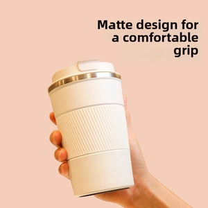Close-up of a hand holding a white matte insulated coffee mug with silicone heat sleeve