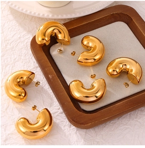 Detailed close-up of polished 18K gold-plated C-shaped stud earrings on a display tray
