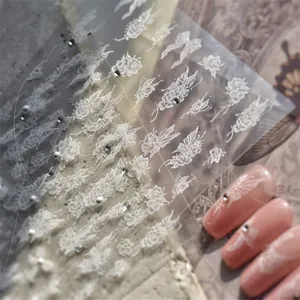 Detail of white embossed nail stickers with lace flower and bow patterns on stone background