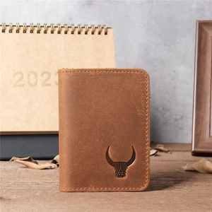 Close-up of vintage brown leather wallet with embossed bull logo on wooden desk