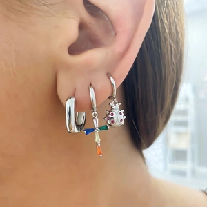 Three-piece set of U-shaped silver hoop earrings with colorful charms on a female model