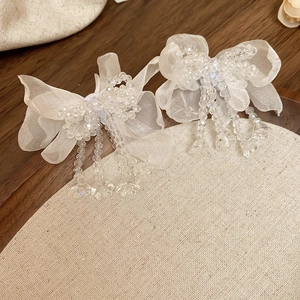 Close-up of white organza ribbon earrings with elegant glass beaded tassels