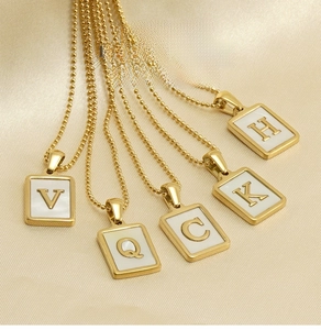 Detail of 18K gold-plated square pendants with natural shell inlay and capital letters