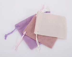Detailed texture of velvet drawstring jewelry pouches in purple, pink, and beige colors