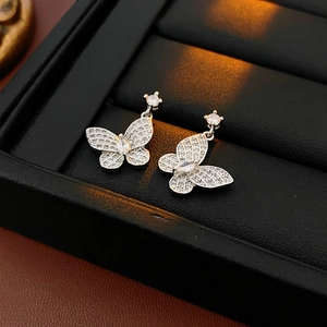 Close-up of butterfly stud earrings with sparkling zircons on a luxury black leather case