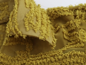 Detailed macro view of ginger yellow textured fabric with fuzzy floral embroidery patterns
