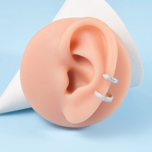 Detailed view of silver cuff earrings with pavé zircons on a silicone ear model