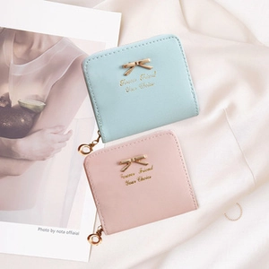 Detail view of mini square PU leather wallets with golden bow and wrap-around zipper
