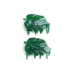 Detailed view of two green monstera leaf hair claws made of glossy acetate material