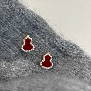Macro detail of gold-plated red enamel gourd earrings with sparkling zircon inlay