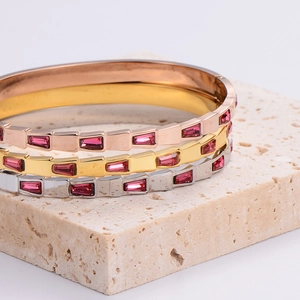 Set of three stainless steel bangles in gold, silver, and rose gold with pink gemstones