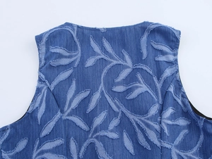 Detail of blue denim vest featuring unique jacquard leaf patterns and raw fringe edges