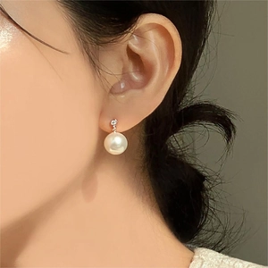 Close-up of elegant pearl drop earring with zircon accent worn by a model
