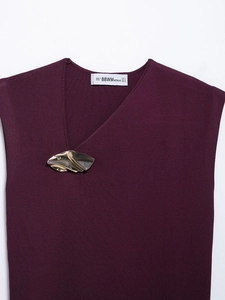 Detail of cross V-neck knitted top in deep purple with unique gold metal ornament