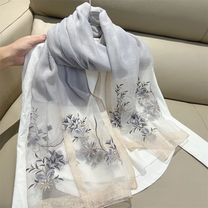 Detail of grey gradient scarf featuring delicate floral embroidery and gold glitter trim