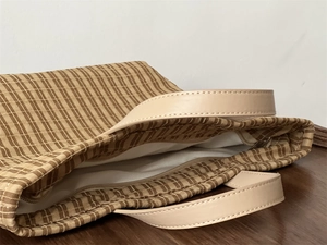 Detail view of the brown plaid canvas tote bag with leather handles and white lining