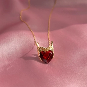 Détail du collier coeur rouge en zircon avec couronne dorée sur soie rose douce