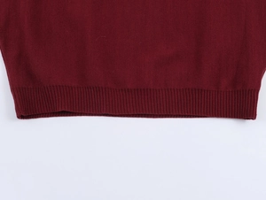 Detailed close-up of dark red knitted top featuring ribbed hem and fine stitching