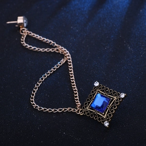 Detail of vintage gold square brooch with blue gemstone and elegant tassel chains