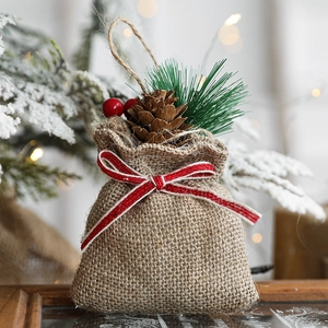Linen Christmas gift bag ornament with pine cones and red berries on a snowy tree