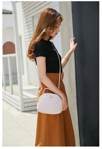 Detail of white quilted crossbody bag with golden flower clasp and chain strap