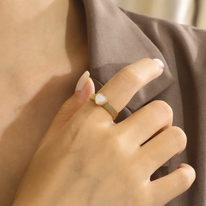 Elegant gold woven mesh ring with a heart-shaped shell inlay worn on a finger