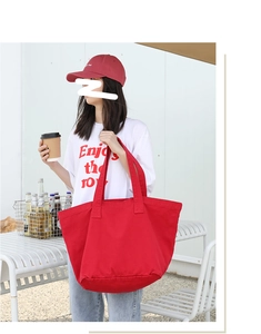 Close-up of a large red canvas tote bag with thick durable straps for daily commuting