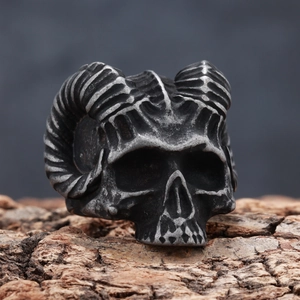Detail of vintage ram skull ring with oxidized metal texture on a rustic wood background